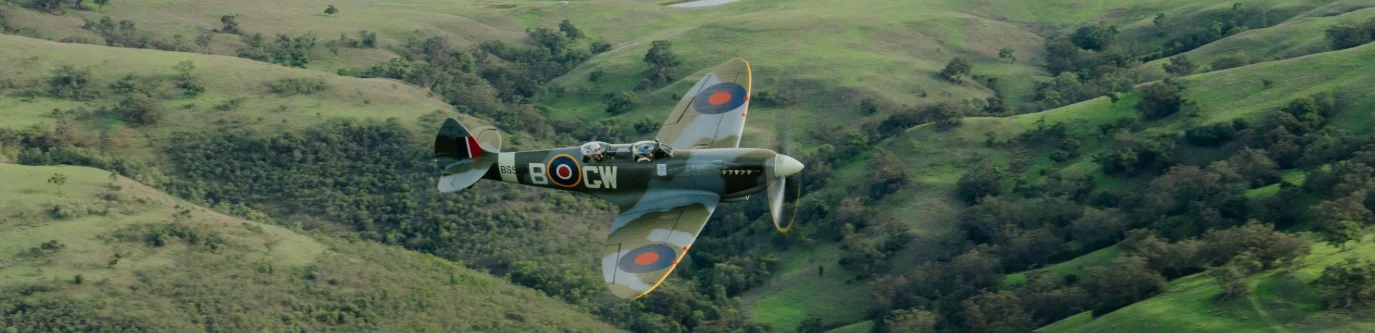 Spitfire VH-TR9 in flight over open country